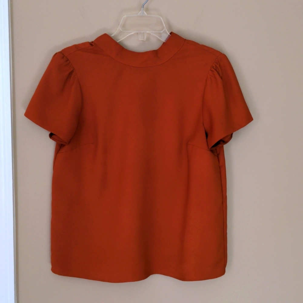 Women's rust colored short sleeve blouse with button neck detail in the back
